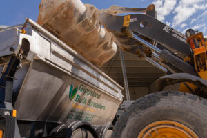 image of tractor with tipper attachment loading premium bulk spread and fertiliser into Gippsland Bulk Spreaders trailer for delivery